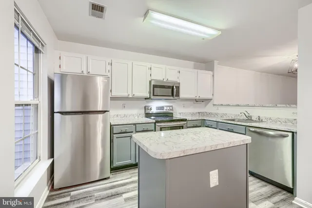 a kitchen with stainless steel appliances granite countertop a refrigerator a stove a sink a microwave and white cabinets