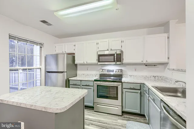 a kitchen with kitchen island a sink stainless steel appliances and white cabinets