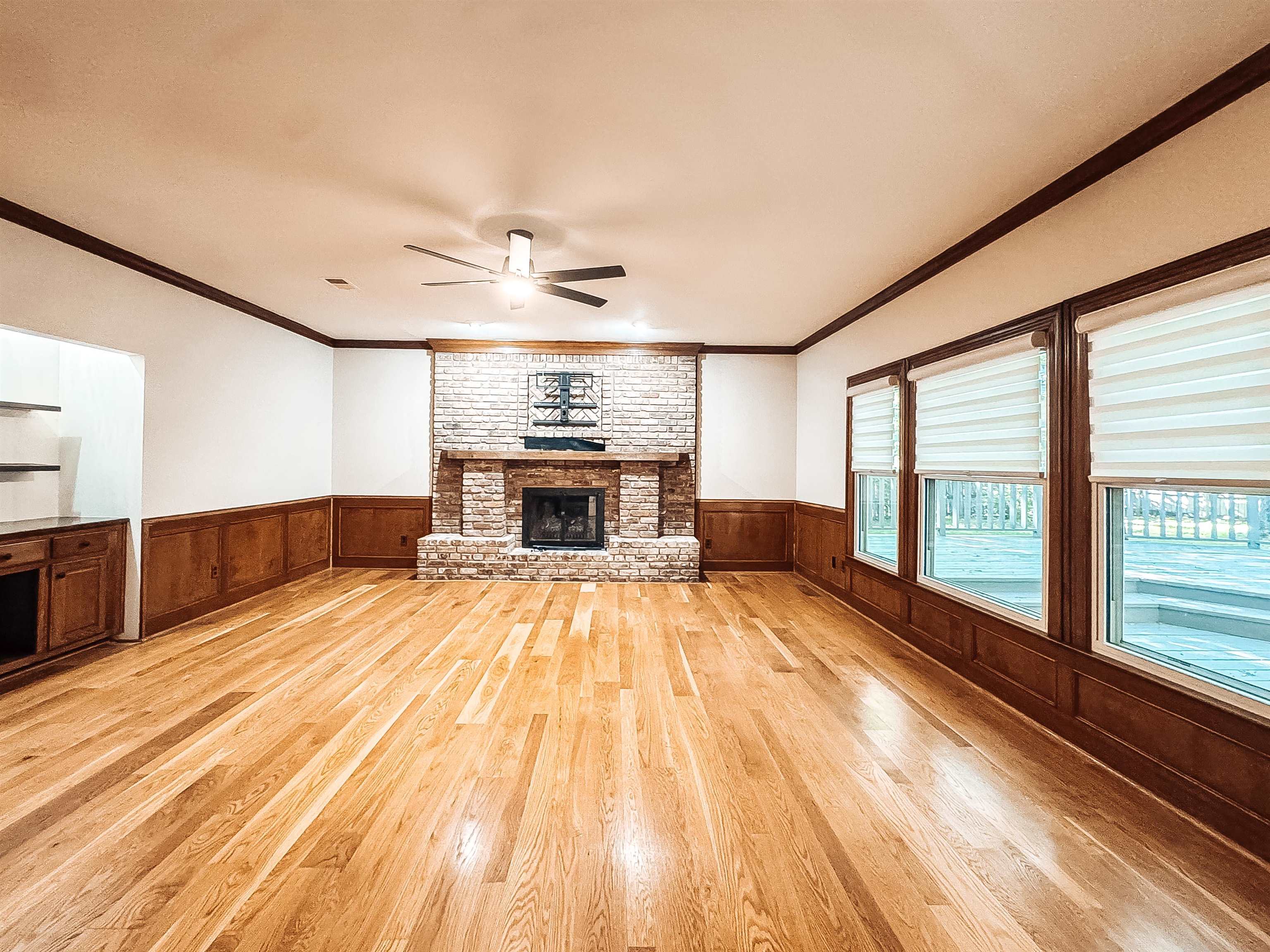 832 South Tree Drive Collierville, TN 38017 - Photo 16 of 40 Spacious room featuring wood-finish flooring, a brick fireplace with a wood mantle, wainscoting, and large windows with blinds
