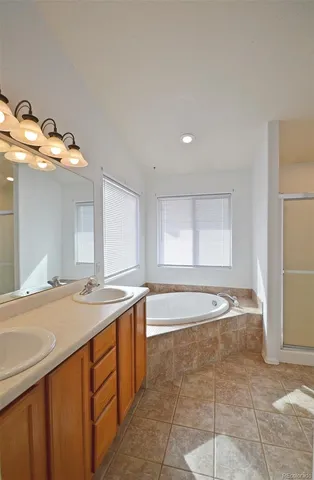 a spacious bathroom with a granite countertop sink a mirror and a bathtub
