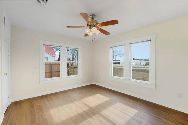 a view of an empty room with a window and wooden floor
