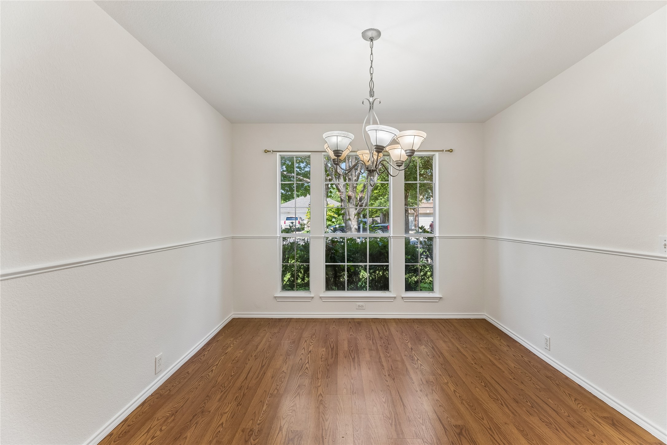 2372 Paradise Ridge Drive Round Rock, TX 78665 - Photo 4 of 40 A refined dining space features hardwood floors, tall windows, and a classic chandelier.