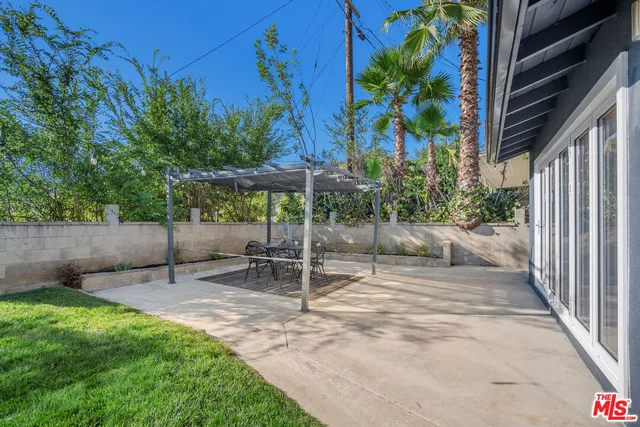 a view of a patio with table and chairs under an umbrella with a small yard