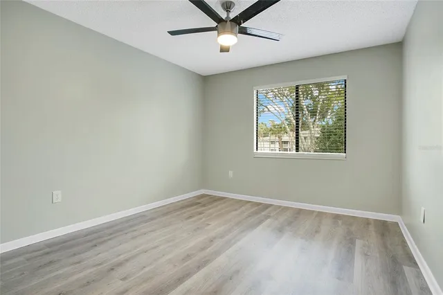 a view of an empty room with window and wooden floor