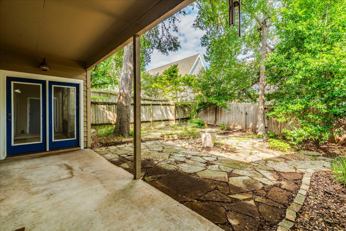 3809 Spicewood Springs Road, Unit 127 Austin, TX 78759 - Photo 22 of 29 An inviting covered patio opens to a tranquil backyard featuring a flagstone path and lush greenery.