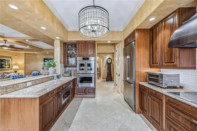 a large kitchen with stainless steel appliances a large counter top a stove and a sink