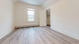 an empty room with wooden floor and window