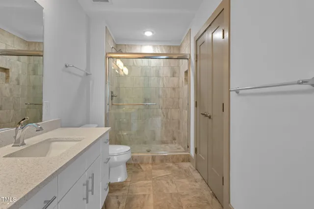 a bathroom with a granite countertop sink a toilet and shower