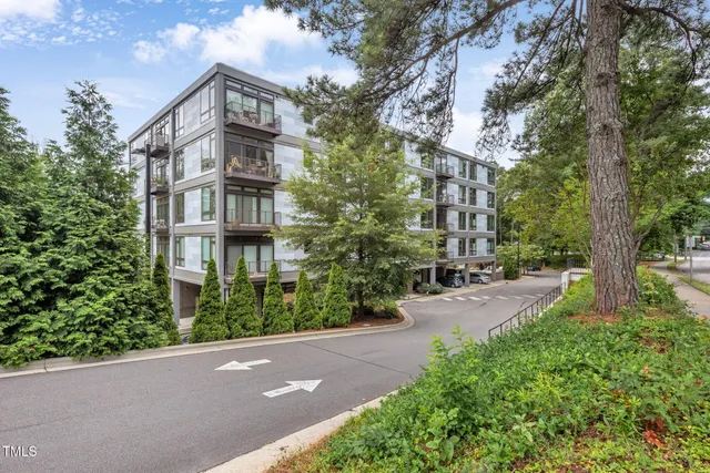 a pathway of a house with a yard and large trees