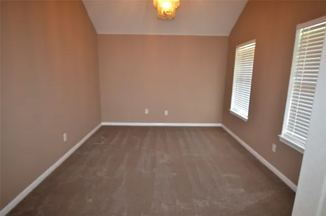 an empty room with windows and chandelier fan