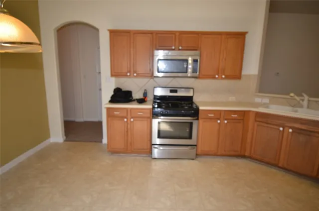 a kitchen with stainless steel appliances granite countertop a refrigerator a stove top oven a sink and dishwasher