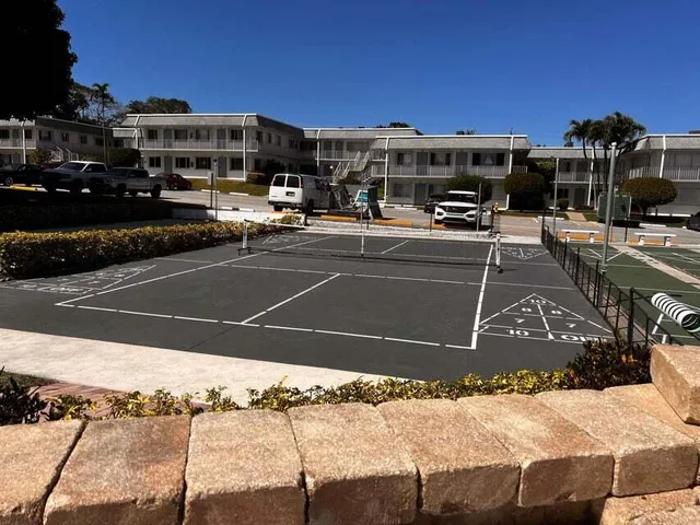 a view of a tennis ground with large trees