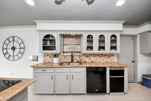 a kitchen with a sink a stove and a clock