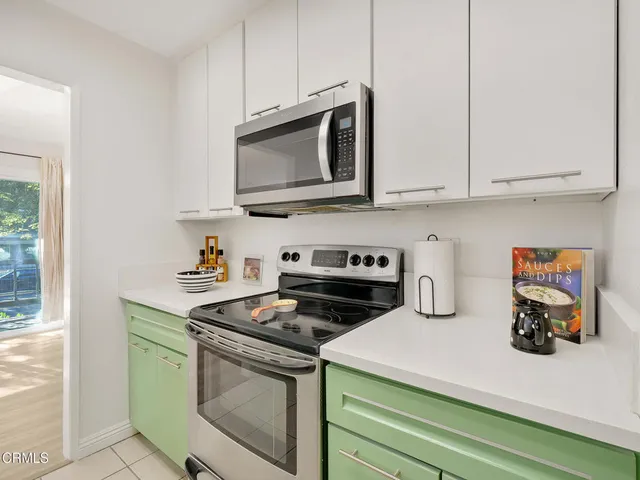 a kitchen with stainless steel appliances a stove a microwave a sink and white cabinets