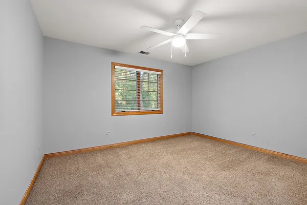 an empty room with windows and fan