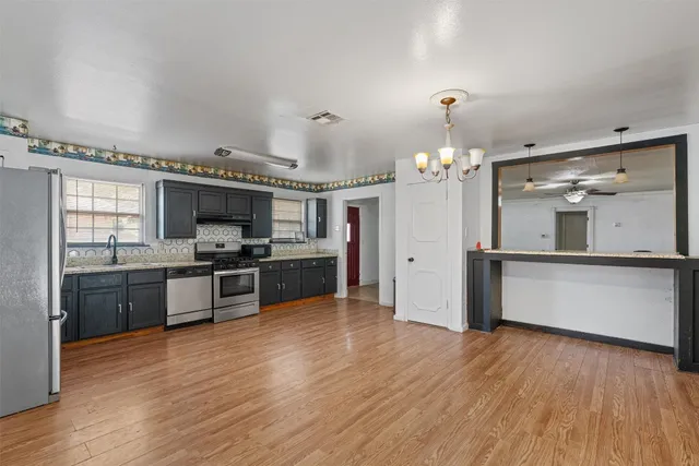 a large kitchen with a wooden floor and stainless steel appliances