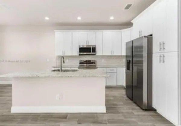 a kitchen with a refrigerator a stove top oven a sink and cabinets
