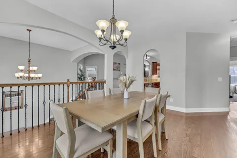 a dining room with wooden floor a chandelier a wooden table and chairs