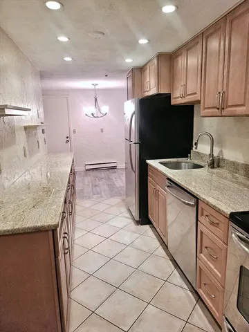 a kitchen with kitchen island granite countertop wooden cabinets and a refrigerator