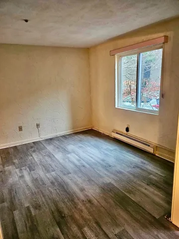 an empty room with wooden floor and window