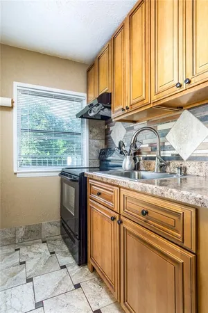 a kitchen with granite countertop a stove a sink and a counter space