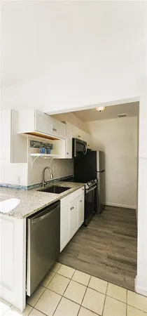 a kitchen with stainless steel appliances granite countertop a sink and stove top oven with wooden floor