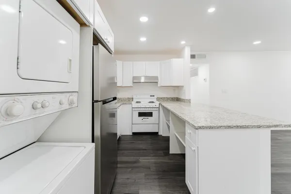 a kitchen with granite countertop white cabinets and white appliances