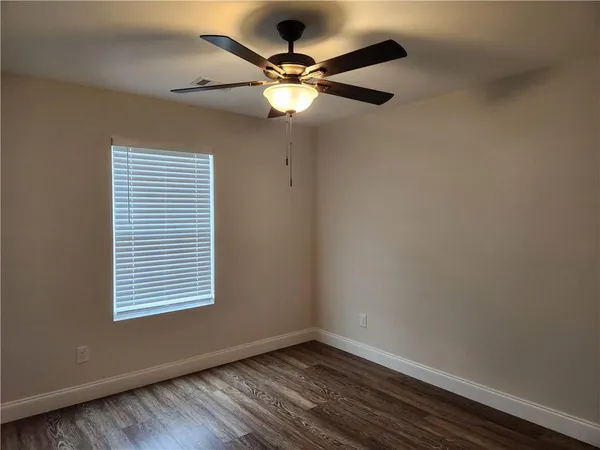 an empty room with window and ceiling fan