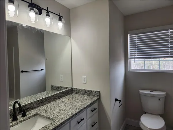a bathroom with a granite countertop sink toilet and mirror