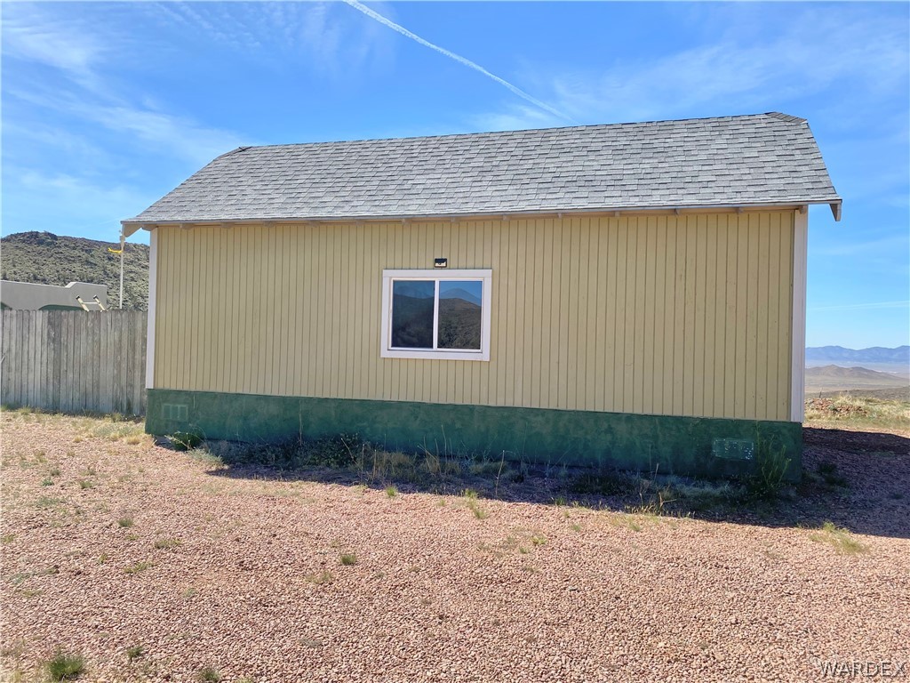 9095 Elliott Ridge Road Kingman, AZ 86401 - Photo 32 of 54 The property features a light-colored exterior with a contrasting lower trim and a gray shingle roof