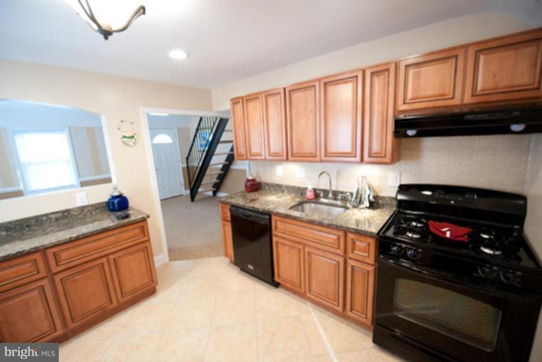 3127 Sollers Point Road Dundalk, MD 21222 - Photo 1 of 14 a kitchen with granite countertop wooden cabinets and a stove top oven