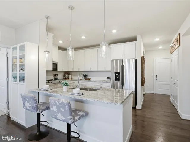 a large kitchen with stainless steel appliances kitchen island granite countertop a refrigerator and a stove top oven