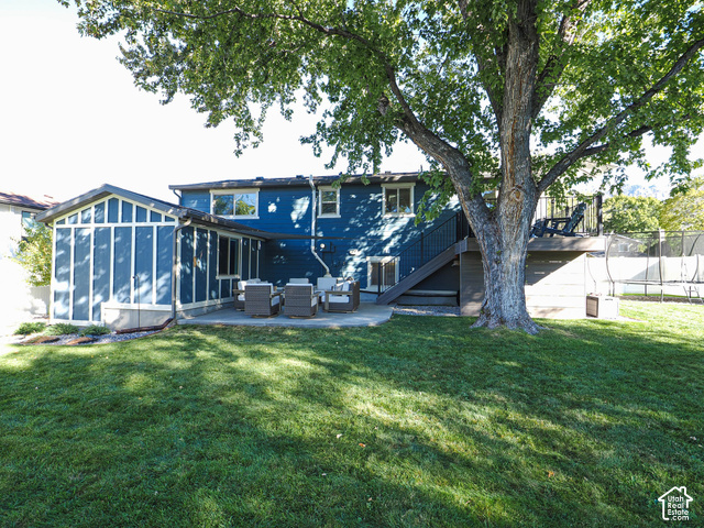 3308 Willow Ridge Road Salt Lake City, UT 84121 - Photo 4 of 59 Expansive lawn area with a large mature tree, concrete patio, and enclosed sunroom addition