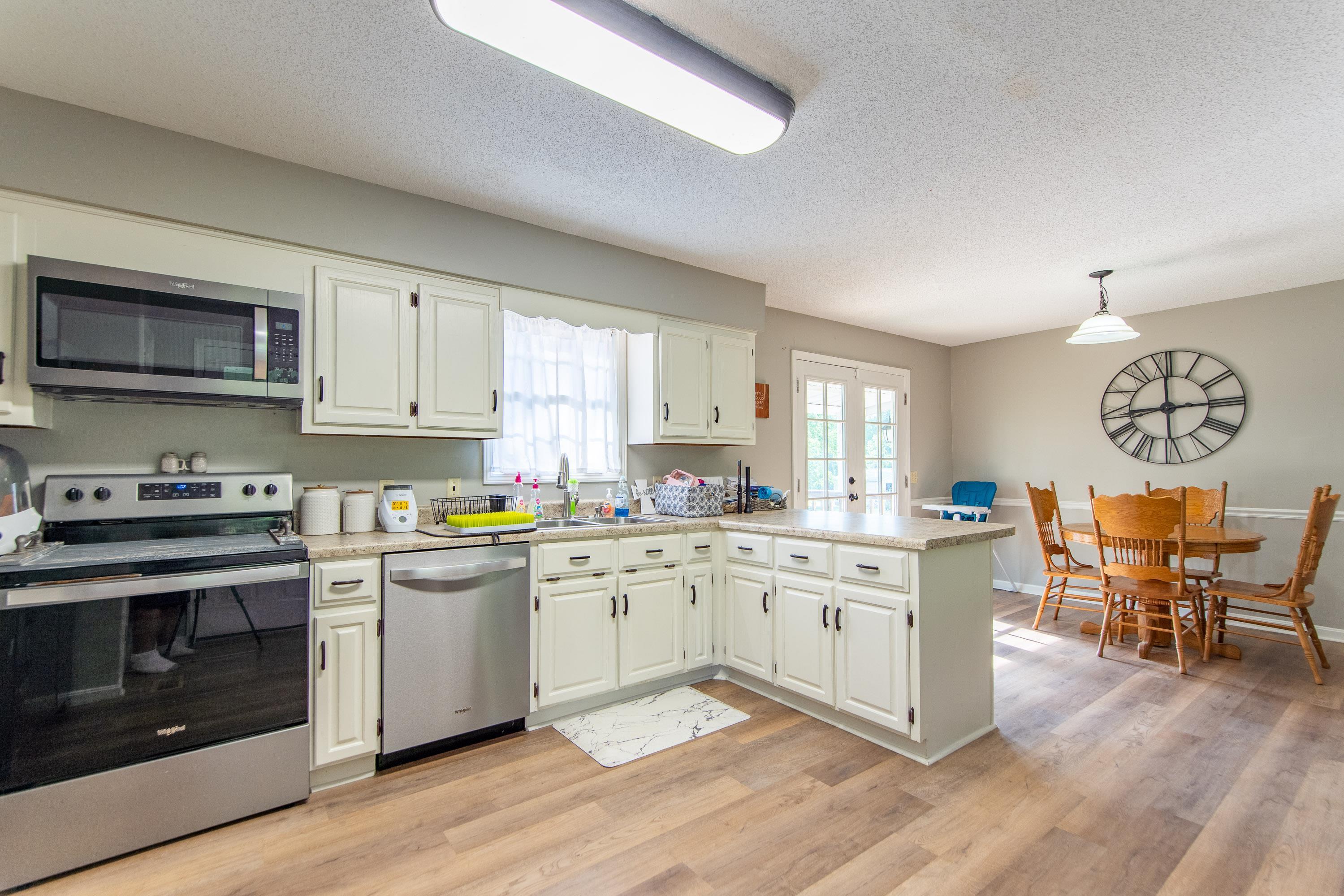 334 Neely Sharp Road Adamsville, TN 38310 - Photo 3 of 25 a kitchen with stainless steel appliances granite countertop a stove top oven a sink dishwasher and white cabinets with wooden floor