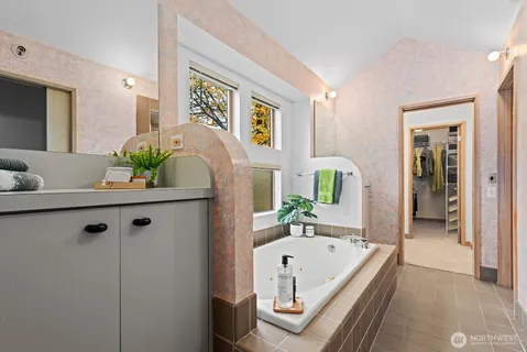 a bath room with a granite countertop tub sink and mirror