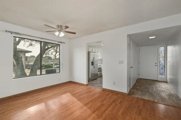 a view of empty room with wooden floor and fan
