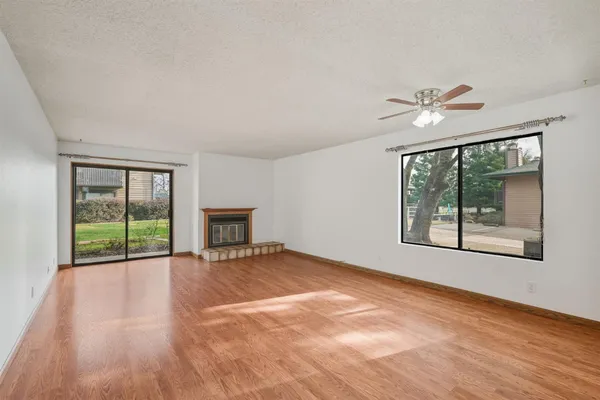 a view of an empty room with a window and wooden floor