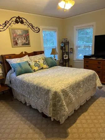 a bed sitting in a bedroom next to a window with a flat screen tv