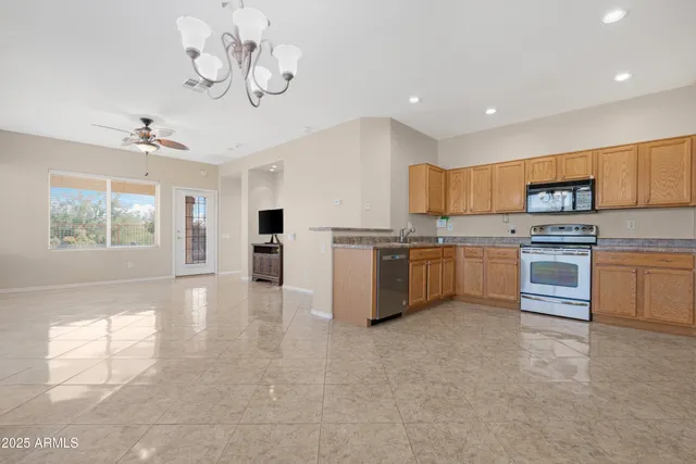 a kitchen with kitchen island a sink a stove a refrigerator cabinets and a window