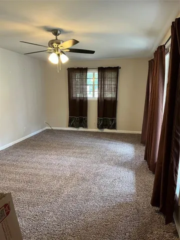 an empty room with windows and chandelier fan
