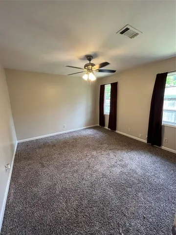 a view of empty room with window and ceiling fan