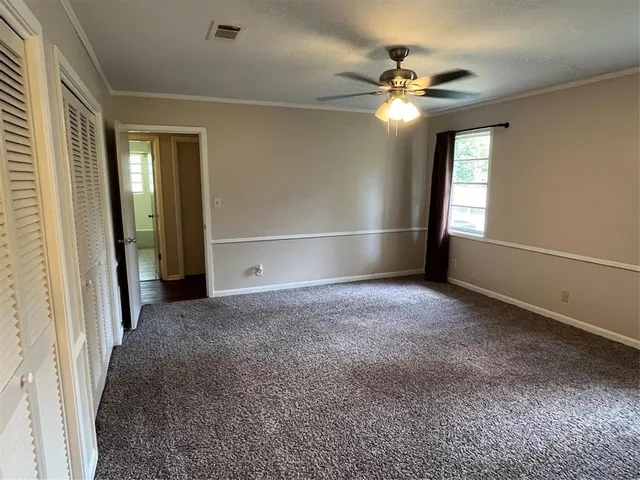 an empty room with windows and fan