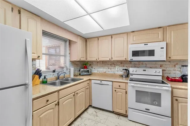 a kitchen with white cabinets white stainless steel appliances and sink