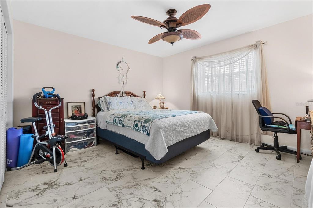 610 Indian Rocks Road North, Unit 103 Belleair Bluffs, FL 33770 - Photo 18 of 23 a bedroom with a bed a chandelier and dresser