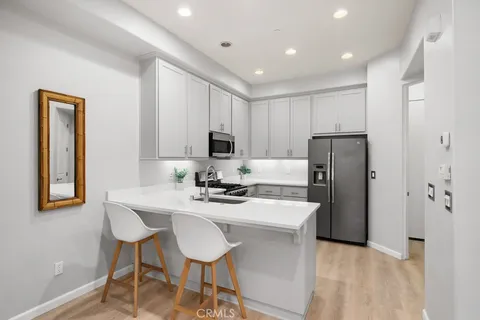 a kitchen with stainless steel appliances granite countertop a refrigerator a sink a stove a dining table and chairs