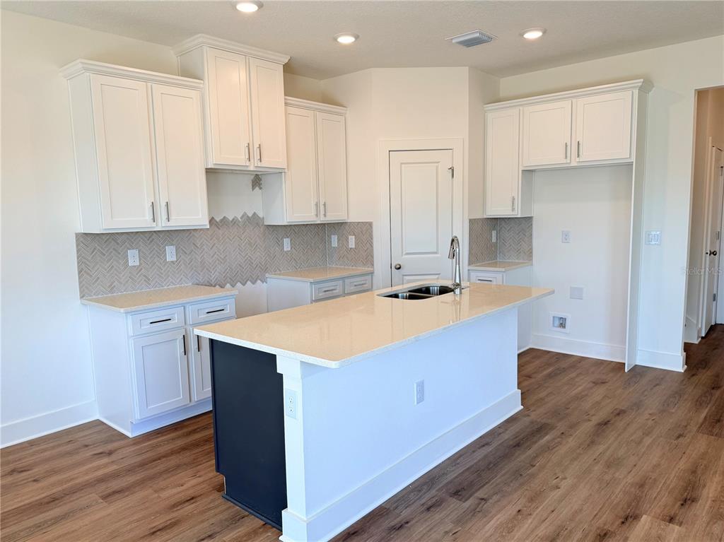 13622 Wolfpack Road Hudson, FL 34667 - Photo 4 of 7 a kitchen with stainless steel appliances granite countertop a sink a stove a refrigerator and white cabinets