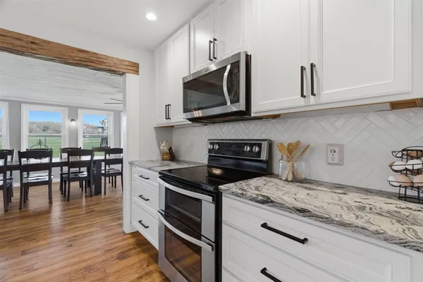 a kitchen with stainless steel appliances granite countertop a dining table chairs refrigerator and sink