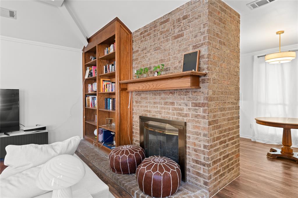 3506 Ruidoso Drive Arlington, TX 76017 - Photo 11 of 37 Brick fireplace with a wood mantel, integrated shelving, and wood-finish flooring