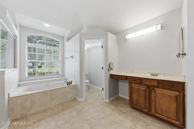 a spacious bathroom with a tub sink and mirror