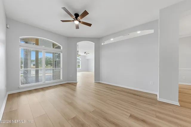 a view of empty room with wooden floor and fan